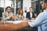 men and a woman interviewing a job applicant